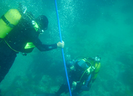 Dos buzos trabajan en el fondeo del cable submarino junto a Alborán.